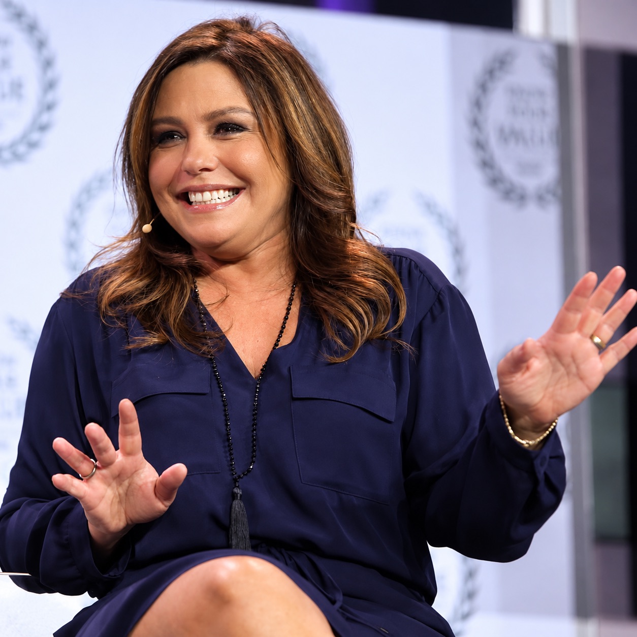 Rachael Ray laughs and gestures mid-conversation on stage.
